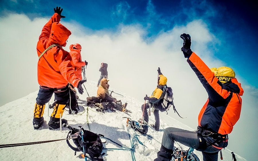 un grupo de personas llega a la cima de la montaña nevada.