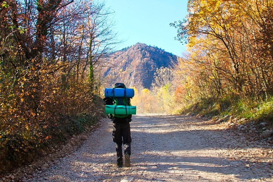 un hombre montañero que lleva su equipaje de acampada.