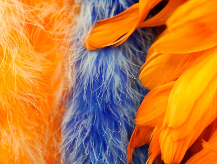 Tres boas de plumas baratas de color naranja y azul.